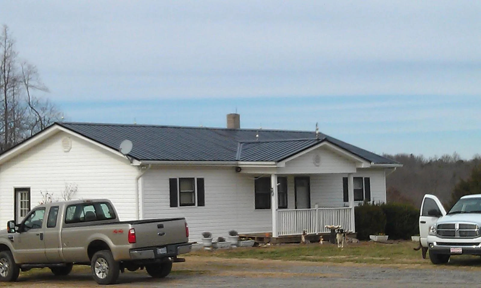 Finished dark metal roof on a white ranch home with work trucks parked in Princeton